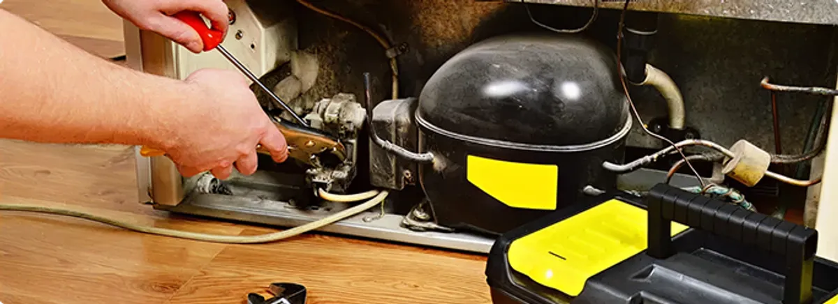 Refrigerator repair technician fixing the compressor and wiring in Carrollton, VA