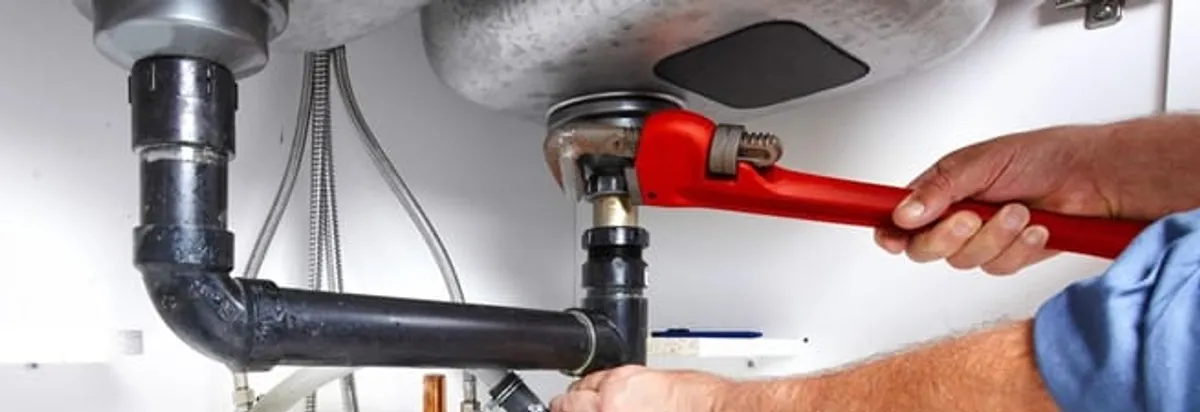 Garbage disposal repair technician tightening the sink drain and disposal connection in Norfolk, VA