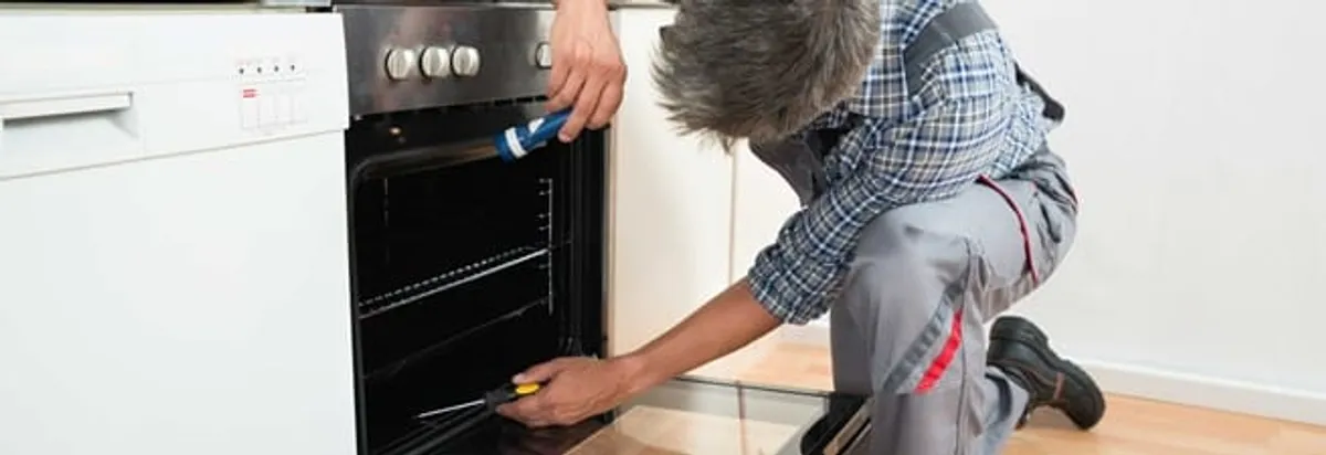 Oven repair technician inspecting and servicing an electric oven in Norfolk, VA