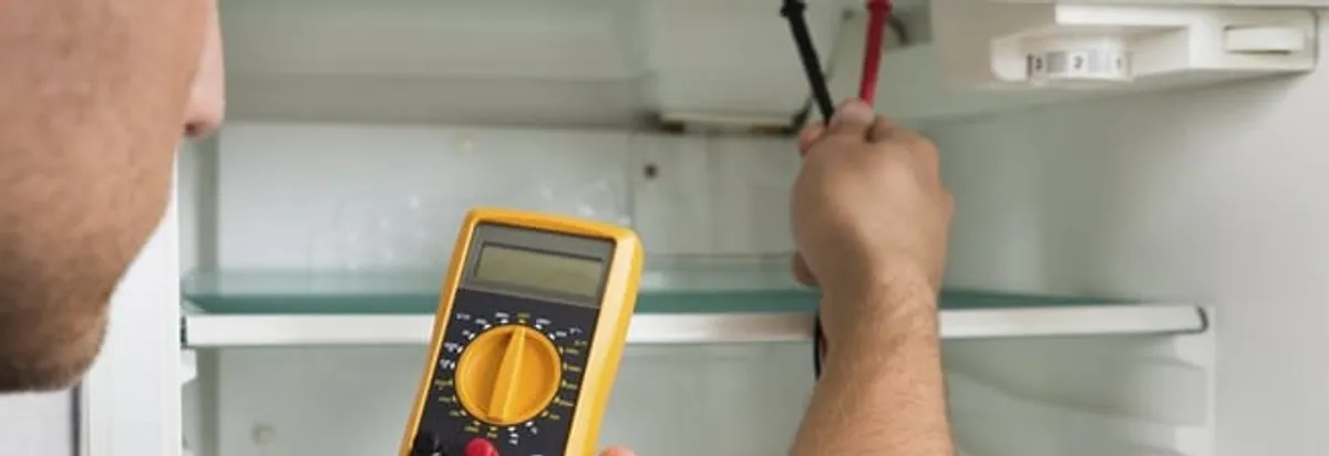 Refrigerator repair technician testing electrical components with a multimeter in Norfolk, VA